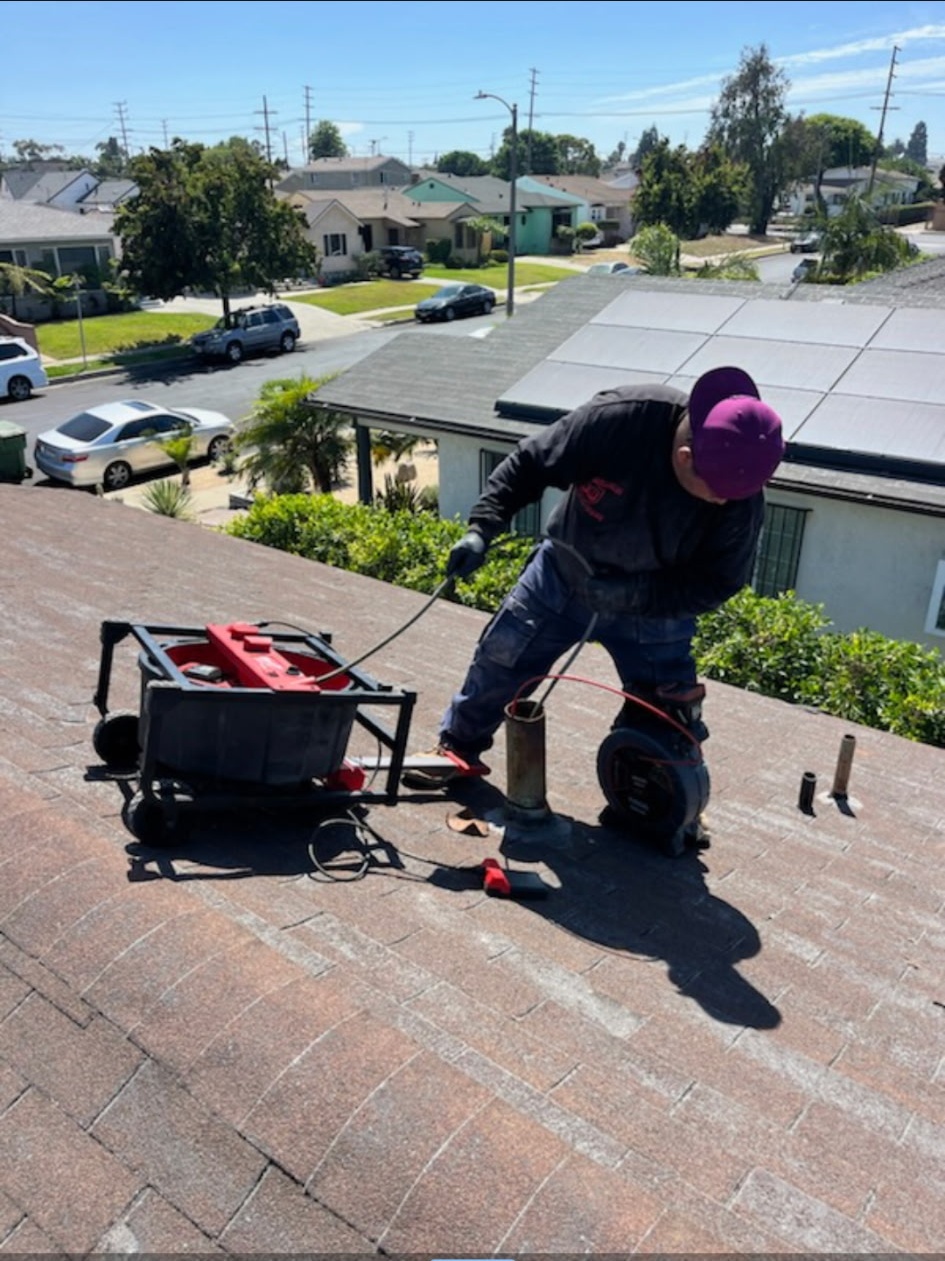 Burris Brothers technician servicing a roof drain in a residential neighborhood
